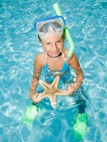 Snorkel girl with starfish in blue water - portrait