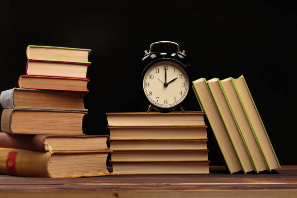 istock Vintage books and clock on wooden table - Image 1155577476