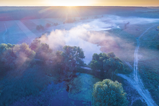 Early misty morning, sunrise over the lake. Rural landscape in summer. Aerial view