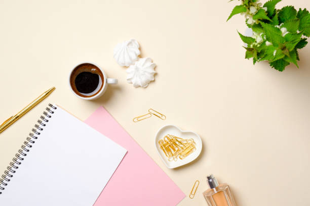 istock Flat lay feminine accessories, blank paper notepad, coffee cup, marshmallow, perfume bottle, flowers on pastel colors beige background. Top view beauty fashion blogger desk with diary and female stuff 1155580026