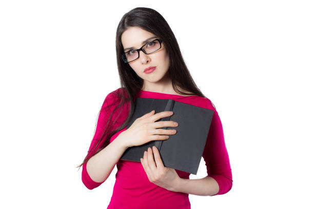 Smart young student woman in red shirt and glasses pressing black book to her heart, on white background, knowledge woman concept idea