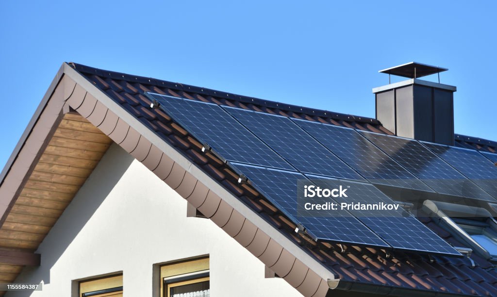 Sonnenkollektoren auf dem Dach eines Hauses mit Fliesen in Europa vor dem Hintergrund eines blauen Himmels installiert. Grüne Technologie - Lizenzfrei Sonnenkollektor Stock-Foto