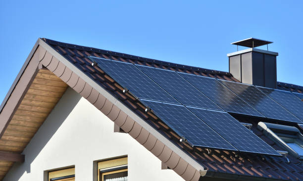 Solar panels installed on the roof of a house with tiles in Europe against the background of a blue sky. Green technology stock photo