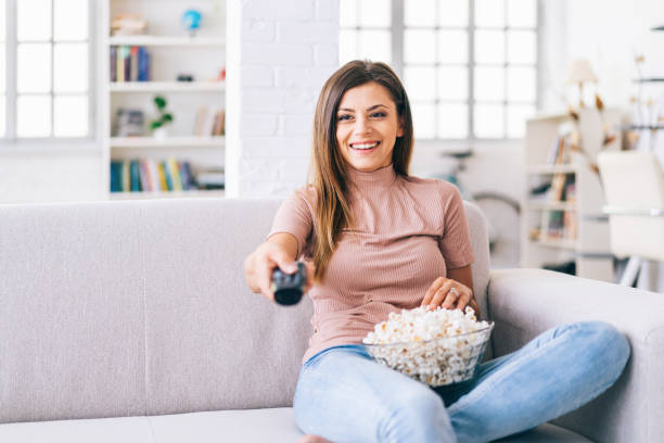 istock Smiling Woman watching a tv at home 1155585431