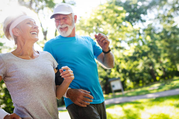 beau couple mature jogging dans la nature vivant en bonne santé - action women sport exercising photos et images de collection