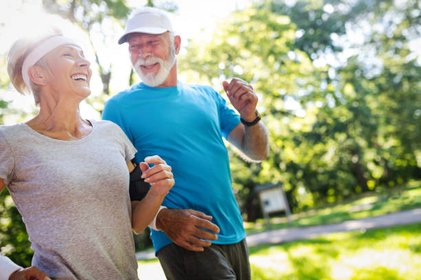 bella coppia matura che fa jogging nella natura vivendo sana - anziani attivi foto e immagini stock
