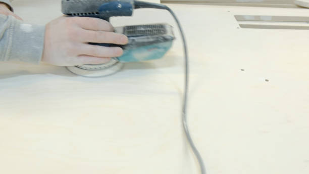 istock Working man with sander grinds wooden surface 1155586636
