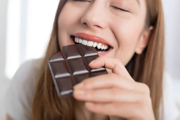 Woman biting a chocolate bar Woman biting a chocolate bar dark chocolate stock pictures, royalty-free photos & images