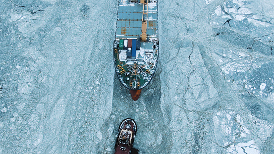 Aerial view. The big ship sails through the sea ice in the winter, close-up.