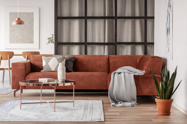 stylowa brązowa sofa narożna z wzorzystymi poduszkami w eleganckim wnętrzu salonu ze ścianą szprosów - mullions zdjęcia i obrazy z banku zdjęć