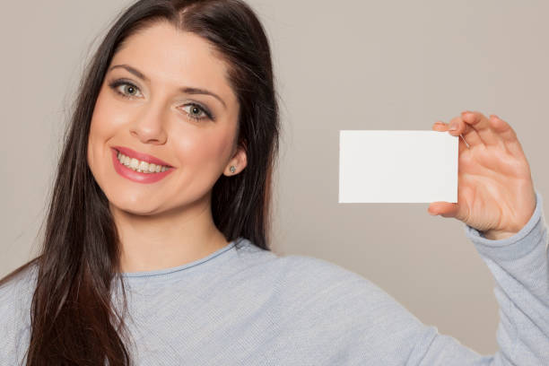istock Smiling woman showing empty blank paper card sign with copy space for text 1155602763