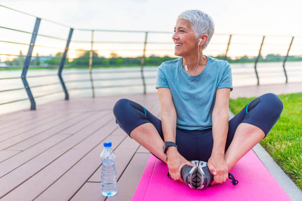 Relaxing after training. Relaxed athletic mature woman sitting on fitness mat outdoors. Senior Woman Resting After Exercises. Woman on a yoga mat to relax outdoor. Senior lady prefers healthy lifestyle eastern european 50s mature women beauty stock pictures, royalty-free photos & images