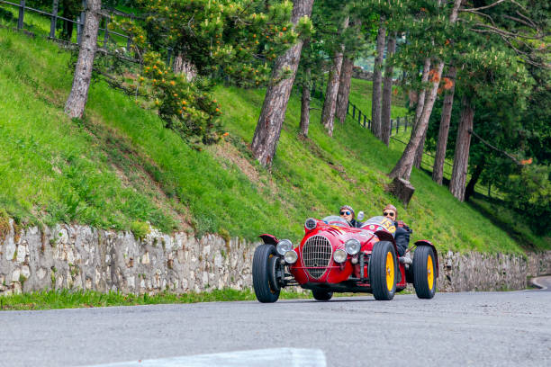 The historic Mille Miglia car race. Two men rushing in a beautiful red vintage car on the race Mille Miglia on the road in the castle of Brescia 1000 Miles 2019, Brescia - Italy. May 15, 2019: The historic Mille Miglia car race. Two men rushing in a beautiful red vintage car on the race Mille Miglia on the road in the castle of Brescia brescia stock pictures, royalty-free photos & images
