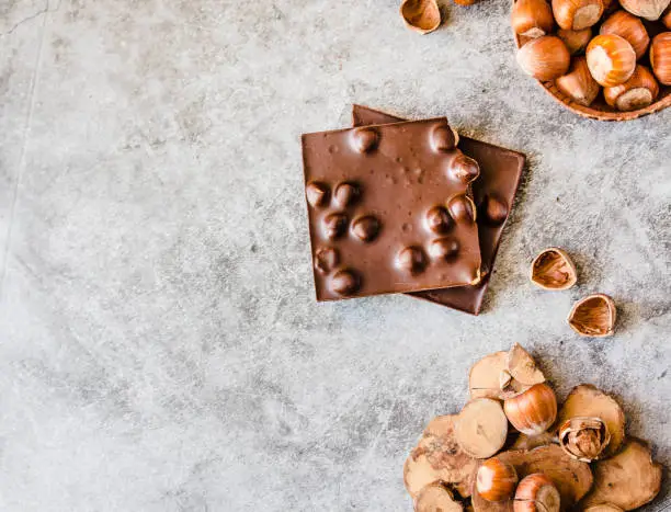 Photo of Homemade hazelnut chocolate bar. Nuts and chocolate background. Ingredients for cooking homemade chocolate sweets. Confectionery and sweets concept