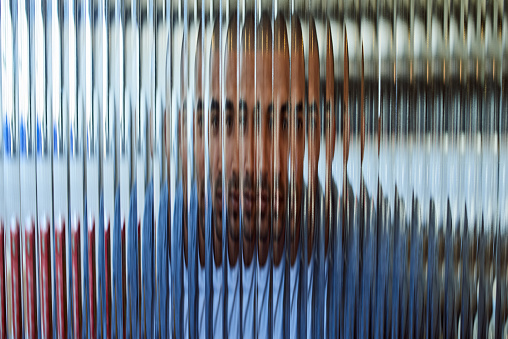 Shot of a handsome young man posing behind a glass surface