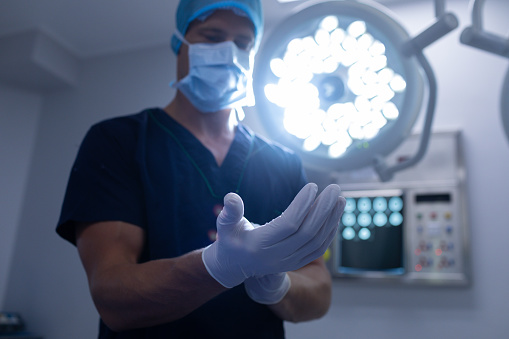 Low angle view of Caucasian male surgeon wearing surgical gloves in operation theater of hospital