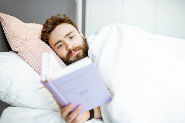 istock Man reading book in the bed 1155609676