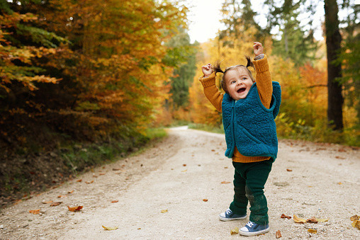 cute little girl in autumn nature laughing and enjoying day.