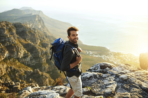 Shot of a young man hiking up a mountain