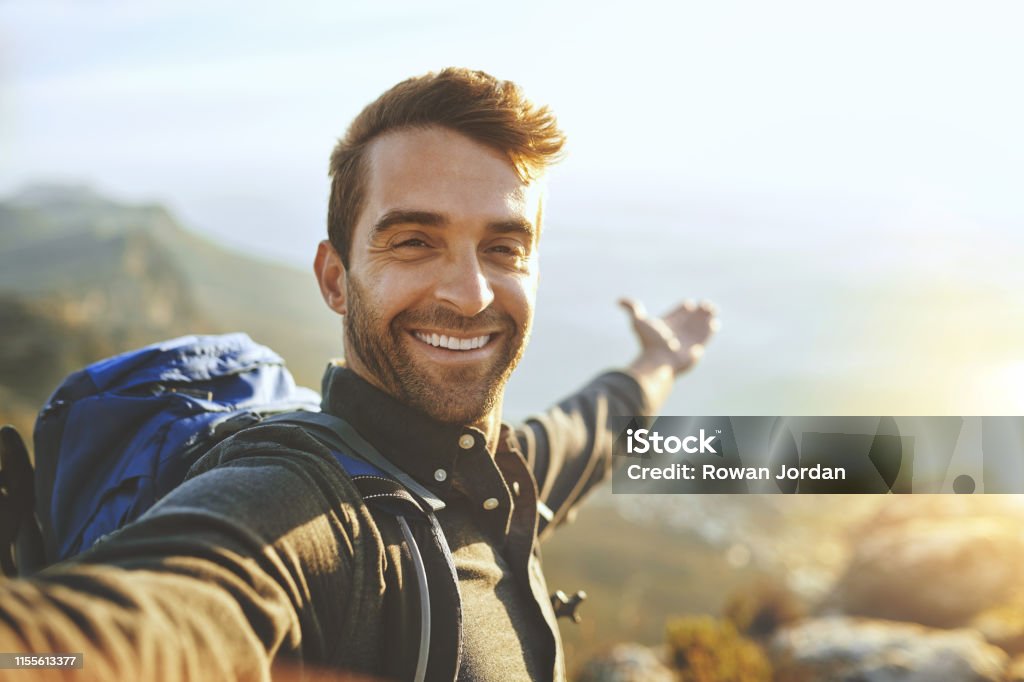 This...is what it's all about Shot of a young man taking selfies while hiking up a mountain Men Stock Photo