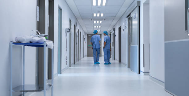 Surgeons talking with each other in the corridor at hospital stock photo