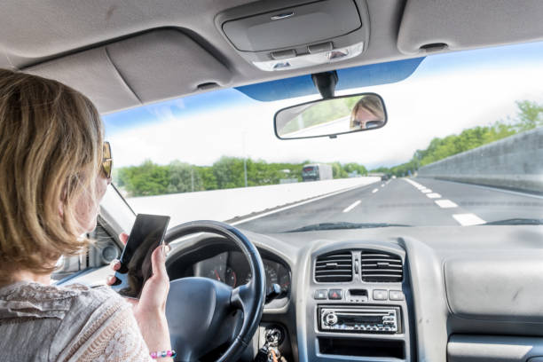 istock Careless Woman Using Phone while Driving a Car on a Highway 1155615525