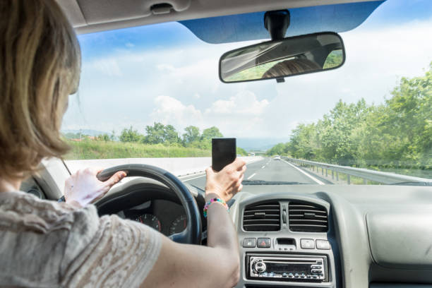 istock Careless Woman Using Phone while Driving a Car on a Highway 1155615530