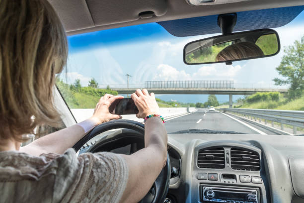 istock Careless Woman Using Phone while Driving a Car on a Highway 1155615537