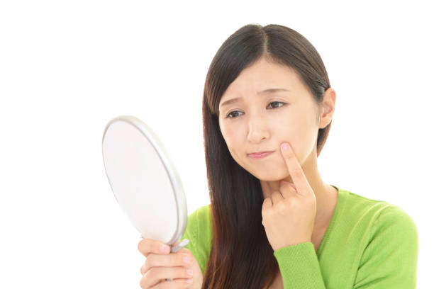 istock Woman looking at her face with hand mirror 1155620951