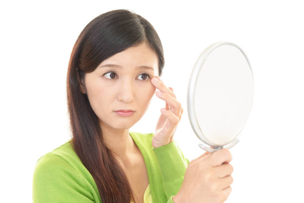 istock Woman looking at her face with hand mirror 1155621027