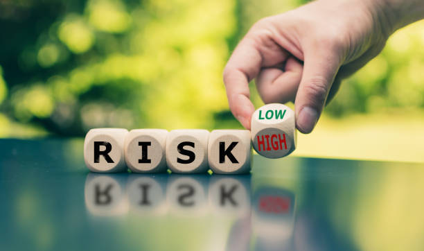 リスクを軽減するためのシンボルです。キューブは "risk" という単語を形成し、手はキューブを回転させ、"high" という単語を低に (またはその逆) に変更します。 - 危険 ストックフォトと画像