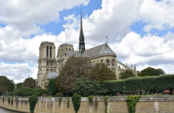 Paris, France. View of Notre Dame Cathedral from Seine river walk with trees. Roofs and Spire detail.