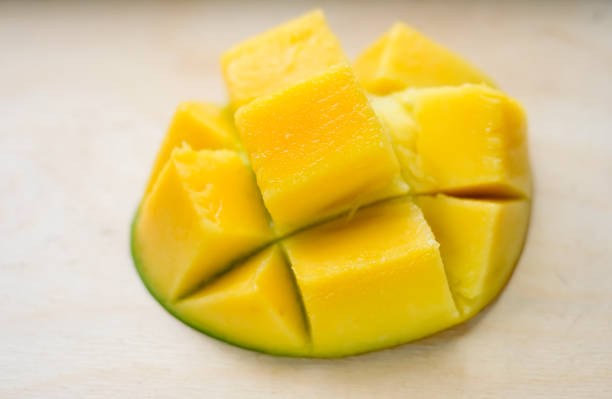 Ripe juicy yellow exotic mango cut into cubes on wooden background. Tropical delicacy full of vitamins for a healthy diet. Closeup. Selective focus. stock photo