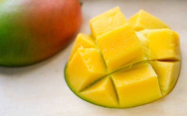 Ripe juicy yellow exotic mango cut into cubes on wooden background. Tropical delicacy full of vitamins for a healthy diet. Closeup. Selective focus. stock photo