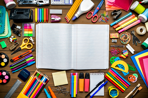 Back to school themes. Overhead shot of stationery on wood desk with paper notepad and frame of school office supplies