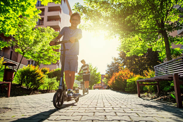 miúdos que montam scooters na área residencial da cidade. - urban nature - fotografias e filmes do acervo