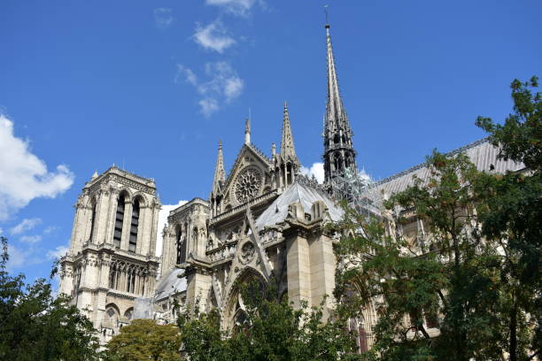 Notre Dame Spire (La Fleche) and lead clad wooden roofs. Paris, France. Paris, France. View of Notre Dame Cathedral from Seine river walk with trees. Roofs and Spire detail. fleche stock pictures, royalty-free photos & images
