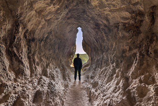 Human birth and light at the end of the tunnel concept. Man standing at the end of a small cave.