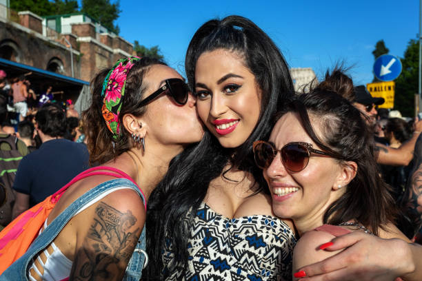 Rome, Italy - June 8, 2019: Gay Pride, public manifestation of gay pride. Three girls in rainbow colors demonstrate in the streets in favor of free love and the rights of homosexuals.
