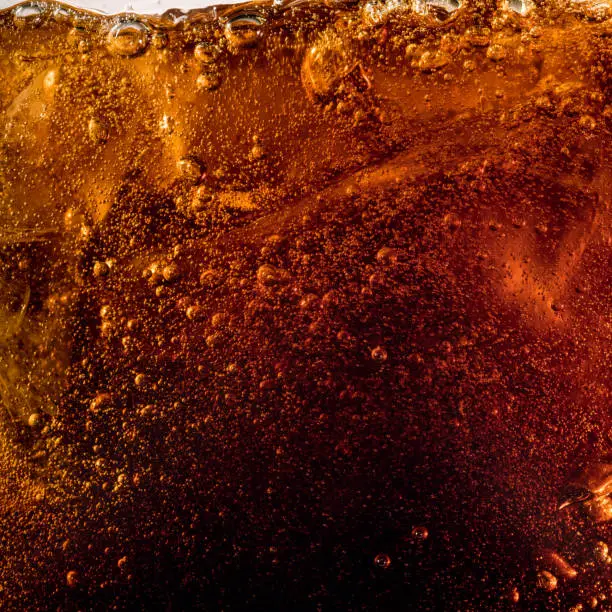 Photo of Close up view of the ice cubes in dark cola background