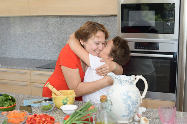 мать и сын обнимаются во время приготовления обеда - family with one child domestic life caucasian love стоковые фото и изображения