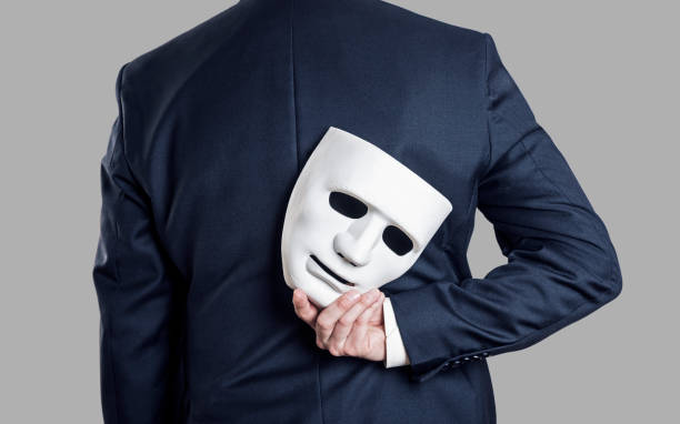 business fraud concept. businessman hide the mask in hand behind his back. - hypocrisy imagens e fotografias de stock