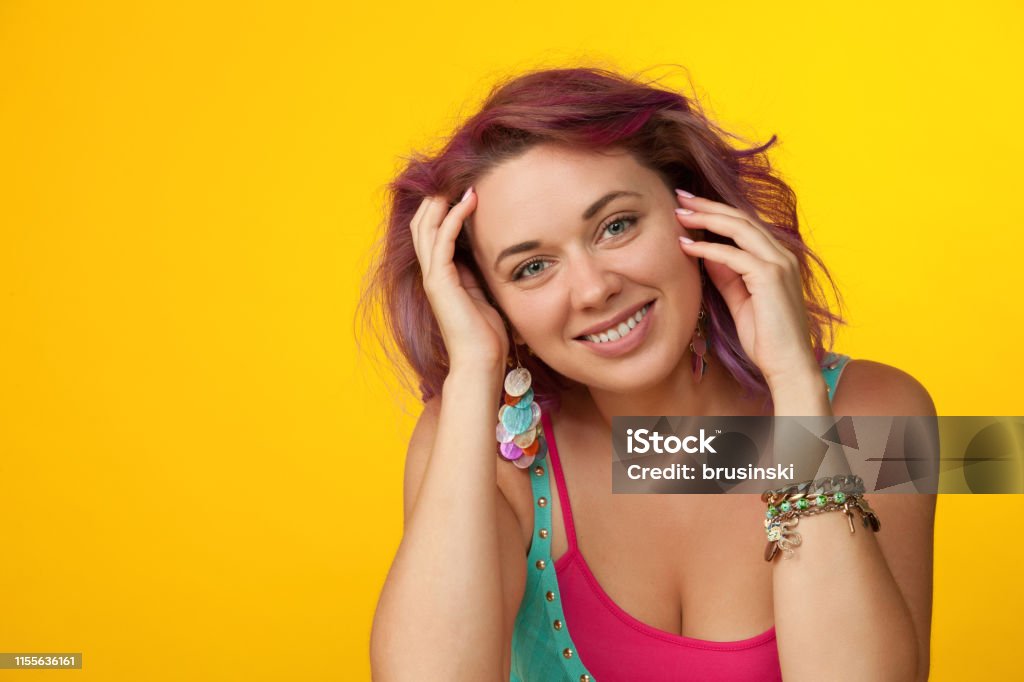 Studio portrait of a 30 year old woman with purple hair on a yellow background 30-34 Years Stock Photo