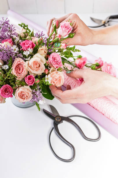 istock Florist at work. Elegant florist hands make bouquet on white background 1155638021
