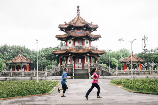 Full length of elderly couple jogging together by shrine. Senior man and woman are in sportswear. They are exercising at park.