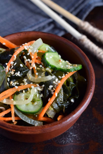 Japanese salad sunomono with wakame, cucumber, onion and carrot sprinkled sesame and chopsticks. Asian raw food The japanese salad sunomono with wakame, cucumber, onion and carrot sprinkled sesame and chopsticks. Asian raw food sunomono stock pictures, royalty-free photos & images