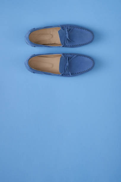 istock Blue suede man's moccasin shoes over blue background 1155645385