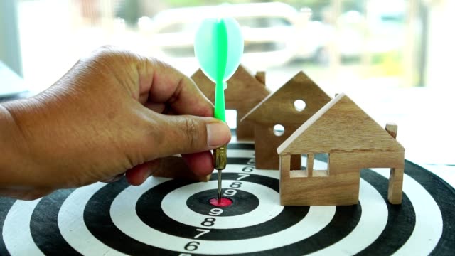 Businessman Hand select green dart arrow and home models on dartboard number target center. Concept of choose mortgage investment asset business and saving money to buy house real estate. 4k shot