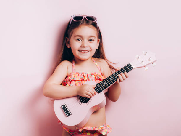 petite fille mignonne dans le maillot de bain jouant le ukulélé. - musical instrument nature outdoors musician photos et images de collection