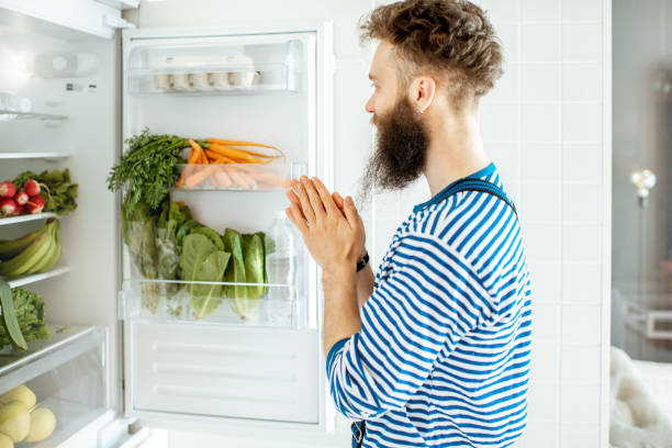 istock Man looking into the fridge with healthy food 1155648317